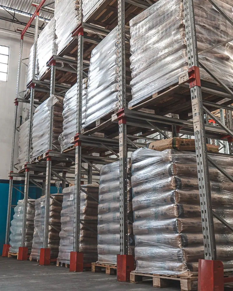 Racks del depósito de secos cargados con bolsas en pallets envueltos en film